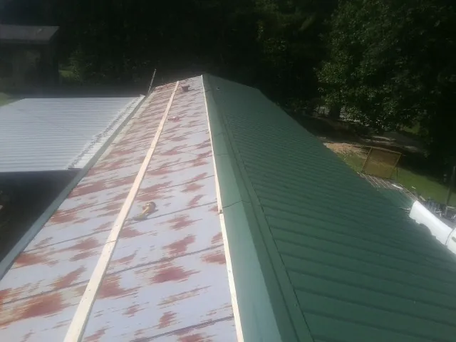 Old rusted panels beside newly installed green metal roofing — Wind Damage Roof Repair by Roofing Brothers in Hamer