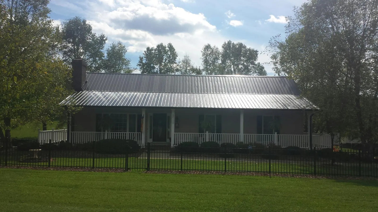Gray metal roof on a brick ranch with a full width front porch — Gutter Guard Installation work by our crew in Hamer